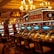 A casino floor featuring rows of brightly lit video poker machines. The area is illuminated by elegant chandeliers, with a display board showing a large sum of money, suggesting a possible jackpot. The rich decor includes luxurious carpets and comfortable seating, adding to the opulent atmosphere.